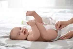 Mother changing her baby's diaper on bed