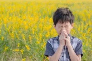 little kid blowing his nose in field