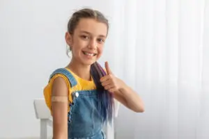 Girl with thumbs up after getting a shot shot. 